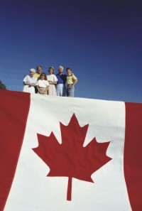 A group of people stands above a large Canadian flag.