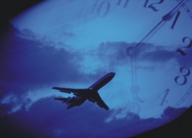 Picture of an airliner in flight with a clock in the background